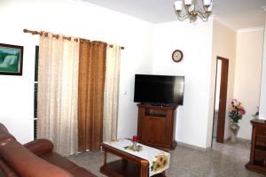 Una sala de estar con un sofá y un televisor de pantalla plana. en Moradia Bela House, en Santa Cruz