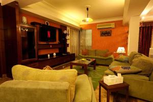 a living room with couches and a flat screen tv at Luxury Apartment 6 min to Airport snacks included. in Cairo