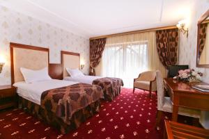 Cette chambre comprend deux lits et un bureau. dans l'établissement Hotel Restaurant La Castel, à Iaşi