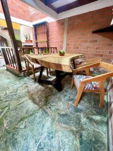 un patio con una mesa de madera, sillas y una pared de ladrillo en Casa Campestre Aware, en Villamaría