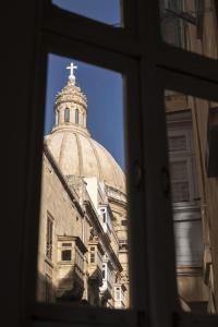 une église avec une croix au-dessus d'un bâtiment dans l'établissement Green door Valletta, à La Valette