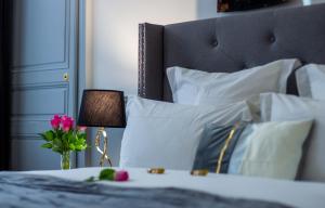 uma cama com almofadas brancas e uma mesa com um candeeiro em La Flûte enchantée em Troyes