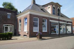 ein Backsteingebäude mit Blumen in einem Mülleimer auf einer Straße in der Unterkunft Bij De Kunstenaars in Ulrum