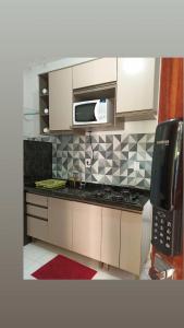 een keuken met een magnetron en een aanrecht bij Apartamento Peterle 101 IRIRI in Anchieta