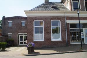 a brick building with white windows and a trash can at Bij De Kunstenaars in Ulrum