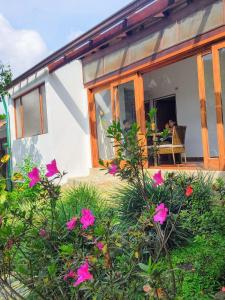 una casa con flores rosas delante de ella en Rincón del colibrí/casa campestre/piscina/la vega, en La Vega