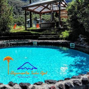 una piscina con sombrilla y cenador en Departamentos en Alojamientos Techo Azul, en Malalcahuello