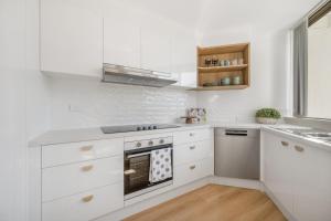 a white kitchen with a stove and a sink at Sundial 202 8-10 Hollingworth Street in Port Macquarie