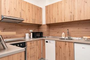 een keuken met houten kasten, een wastafel en een magnetron bij HH apartments in Bjelašnica