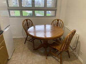 - une table en bois et quatre chaises dans la cuisine dans l'établissement Spacious 2 bed Dulwich flat green views, à Londres