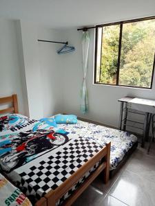 a bedroom with a bed and a desk and a window at Ninfa del Mar Hostal in Manizales