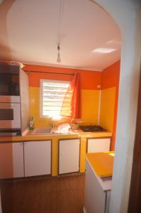 a kitchen with an orange and yellow wall at Bougain Fleuri in Deshaies +6 photos