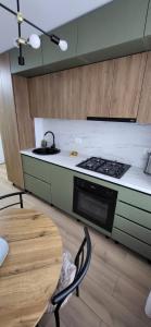 a kitchen with a stove and a sink and a table at Urban Retreat Central - One bedroom apartment in Piteşti