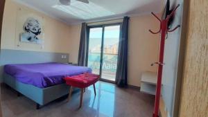 1 dormitorio con cama morada y ventana grande en Apartamento a Duas Quadras da Praia, en Cabo Frío