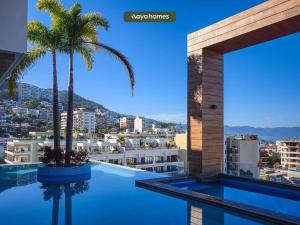 uitzicht op de stad vanaf een zwembad met een palmboom bij Amazing apartment with Rooftop Pool in Puerto Vallarta
