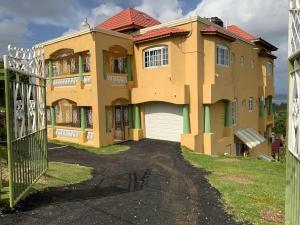a large yellow house with a gate in front of it at POINCIANA APARTMENT ONE 257 POINCIANA DRIVE GREEN WOOD MONTEGO BAY JAMAICA in Montego Bay