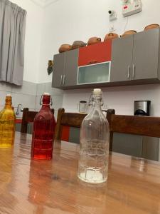 three glass bottles sitting on a wooden table at Hamuy's Lodge in Ica