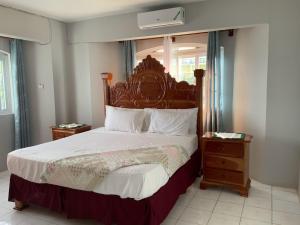Schlafzimmer mit einem großen Bett mit einem Kopfteil aus Holz in der Unterkunft Poinciana House in Montego Bay