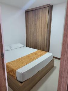 1 dormitorio con 1 cama y armario de madera en Apartamento FL Martinz en Manizales