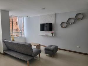 sala de estar con silla y TV en la pared en Apartamento FL Martinz, en Manizales