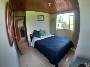 Un dormitorio con una cama azul y una ventana en Hermosa Finca El Porvenir, en Tibasosa