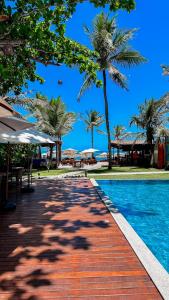 una piscina con palme accanto a un resort di Hotel Pousada Villa Zena - Frente ao Mar - Pé na areia a Arraial d'Ajuda