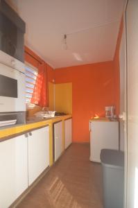 a kitchen with orange walls and white cabinets at Bougain Fleuri in Deshaies