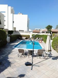 a swimming pool with an umbrella and chairs and a table and an umbrella at Jumeirah Beach Villa in Dubai