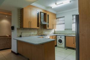 a kitchen with wooden cabinets and a washing machine at Unit 14, Capella Place in East Legon