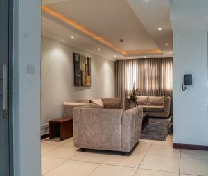 uma sala de estar com duas cadeiras e um sofá em Unit 14, Capella Place em East Legon