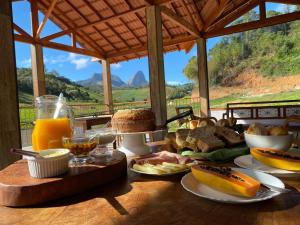uma mesa com pequeno-almoço de pão e sumo de laranja em Pousada Rural Recanto do Lago em Pedra Azul