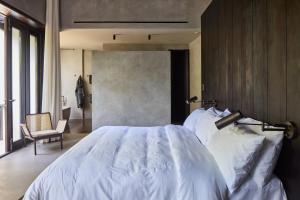 a bedroom with a white bed and a chair at Villa Abrazos in San Pedro