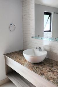 a white bathroom with a sink and a mirror at Grandioso Apartamento. in Quito