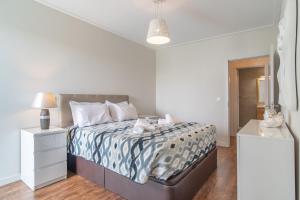 a white bedroom with a large bed and a lamp at Madalenas View in Funchal