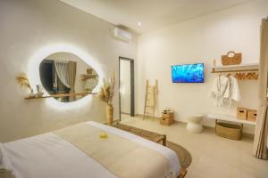 - une chambre blanche avec un lit et un miroir dans l'établissement Santorini Sunset NEW 4 BR villa with beautiful rice paddy view and a large pool, à Canggu