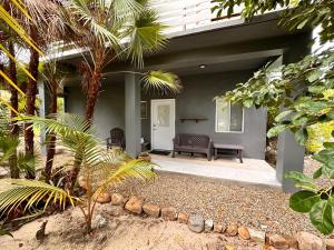 eine Veranda eines Hauses mit einer Bank und Palmen in der Unterkunft La Vida Belize - Studio in Riversdale