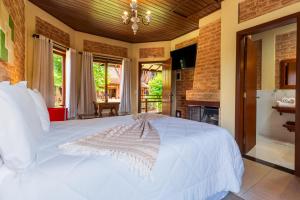 a large white bed in a room with a fireplace at Pousada Boutique Vilage de Minas in Monte Verde