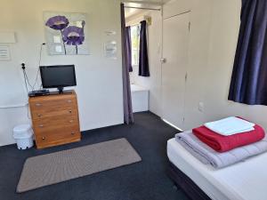 1 dormitorio con cama y vestidor con TV en Picton's Waikawa Bay Holiday Park, en Picton