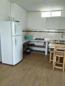 a kitchen with a white refrigerator and a table at Imelda House in Ayangue