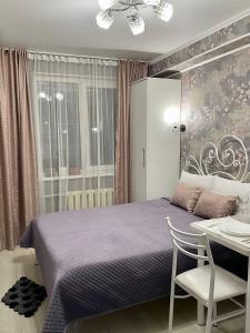1 dormitorio con cama morada, mesa y silla en Уютная комната-студия в центре Бишкека en Bishkek
