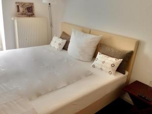 Una cama blanca con algunas almohadas. en Pension Flughafen Leipzig, en Freiroda