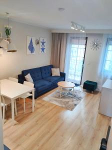 uma sala de estar com um sofá azul e uma mesa em Apartament MajGraj sąsiedztwo Parku Zdrojowego em Świnoujście