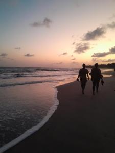 2 personnes marchant sur la plage au coucher du soleil dans l'établissement Afiki, à Ankwanda