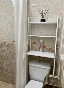 a bathroom with a toilet with a shelf above it at Уютная комната-студия в центре Бишкека in Bishkek
