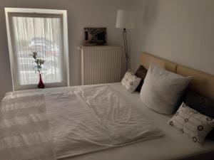 a bedroom with a white bed with pillows and a window at Pension Flughafen Leipzig in Freiroda