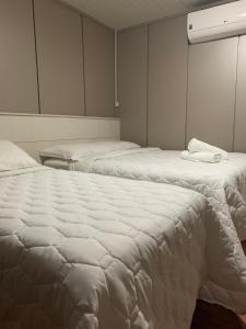 2 bedden in een kamer met witte lakens bij Hotel Morada dos Pinheiros in Bom Jardim da Serra