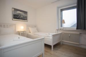a white bedroom with two beds and a window at Appartement Brink Am Waltenberg 57-59 in Winterberg