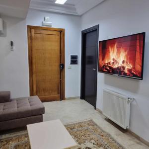 a living room with a fireplace and a tv on the wall at Spacious Apartment Ennasr 2 in Ariana