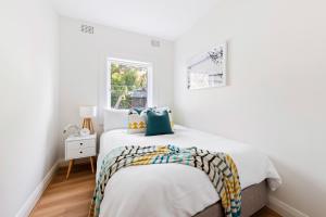a white bedroom with a bed and a window at Little Manly 3 Bedroom Sanctuary in Sydney