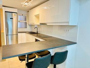 a kitchen with white cabinets and a counter with chairs at APARTMENT WITH OCEAN VIEW in Playa del Cura